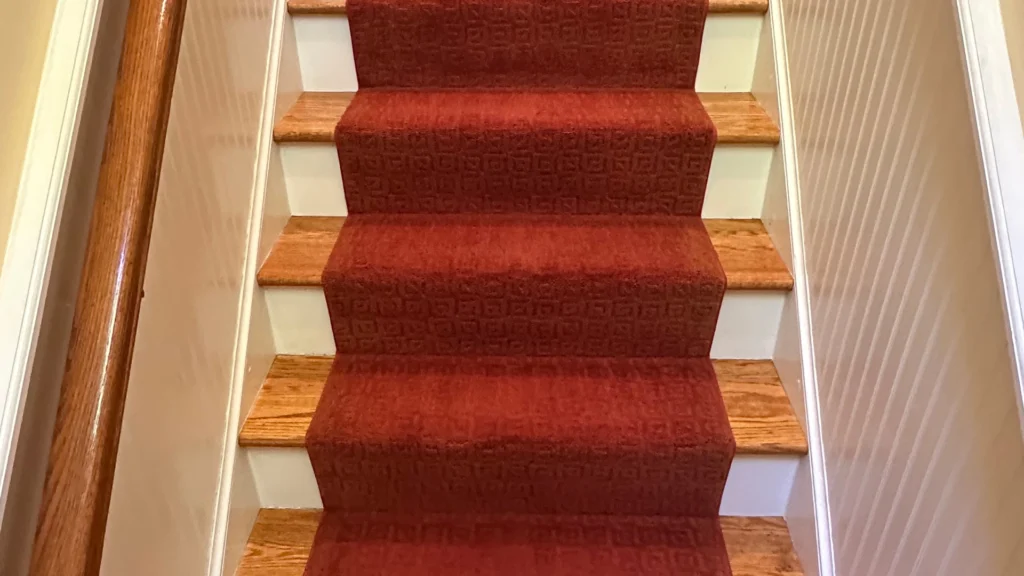 Stairs with red carpet showcasing a clean and well-maintained surface, reflecting stairs carpet cleaning cost benefits.
